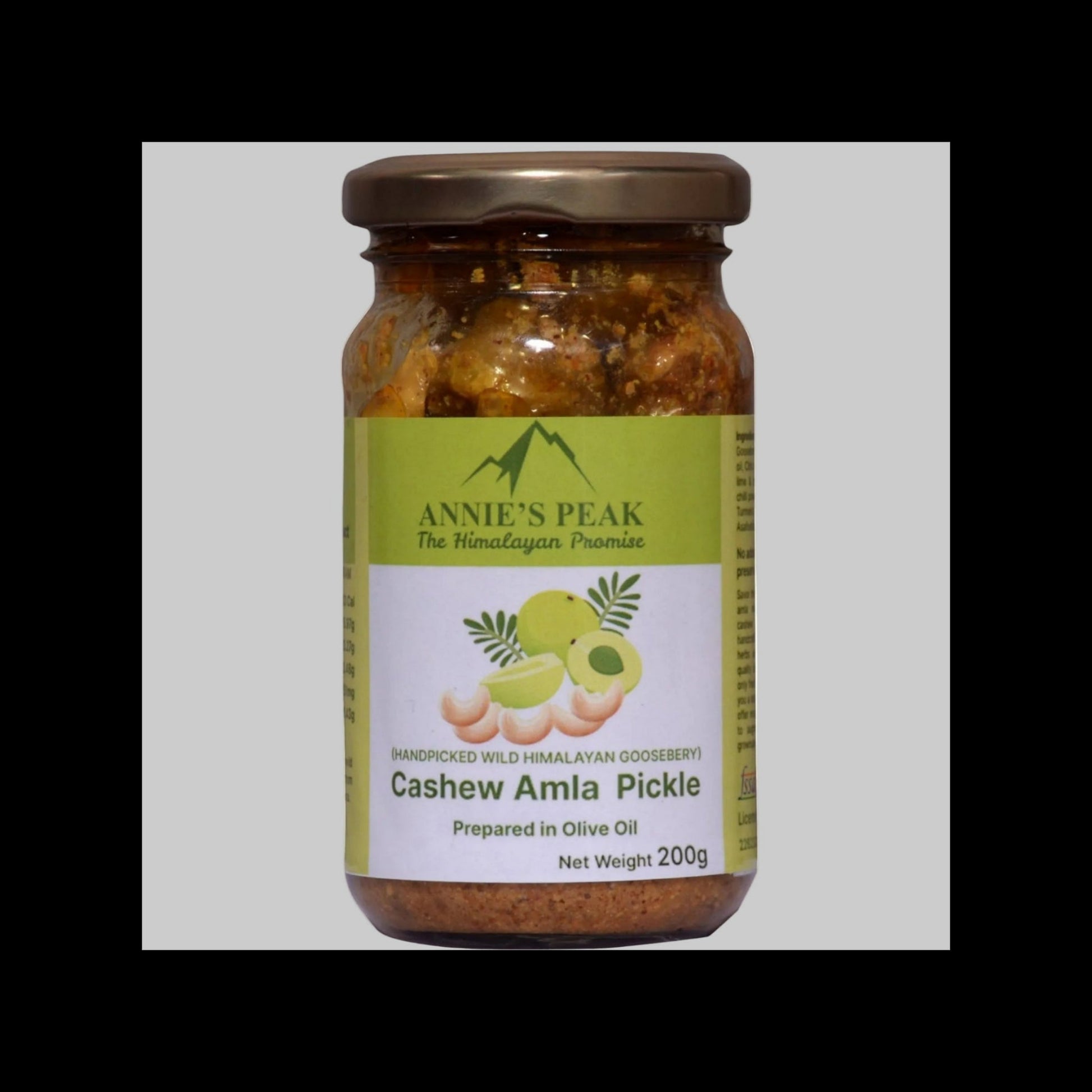 A 200g glass jar of Annie's Peak Cashew Amla Pickle, featuring a green and white label with illustrations of cashews and amla fruit, sealed with a brown metal lid.